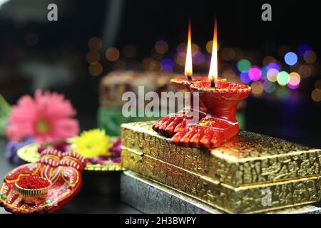 Tonlampe bekannt als Diya, Deep, Diyo, Deepa oder Deepam mit Göttin Füße Lakshmi Charan beleuchtet auf Golden Gift Box mit Bokeh Effekt. Shubh Deepawa Stockfoto