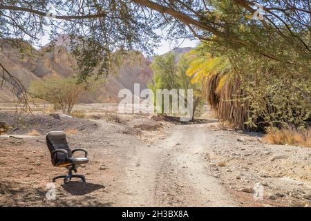 Chaos in der Natur. Umweltverschmutzung durch Menschen. Verlassene Stuhl entlang der schmutzigen Straße, separater Stuhl neben der staubigen Straße. Stockfoto