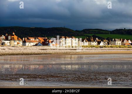 Häuser an der Küste von Llandudno, West Shore Beach, Clwyd, Wales. Dunkle, stürmische Wolken dahinter. Stockfoto