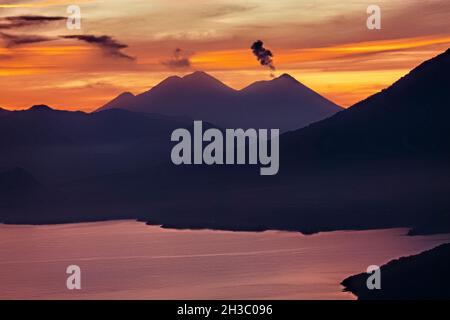 Sonnenaufgang über dem Lake Atitlan und Fuego, Vulkan, Lago Atitlan, Guatemala Stockfoto