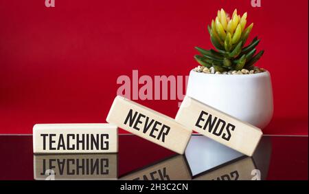 TEXTUNTERRICHT ENDET NIE auf Holzblöcken und rotem und schwarzem Hintergrund mit Kaktusblüte Stockfoto