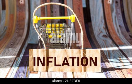 Das Wort Inflation auf dem Preisschild eines Geschäfts, das auf einem leeren Babywagen liegt Stockfoto