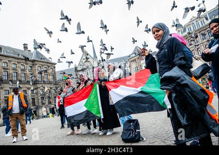 Amsterdam, Niederlande. Oktober 2021. Während der Demonstration fliegen Tauben über eine Gruppe sudanesischer Frauen, die sudanesische Flaggen halten.in den Niederlanden lebende Sudanesen versammelten sich auf dem Dam-Platz im Stadtzentrum von Amsterdam, um gegen den Militärputsch im Sudan zu protestieren. Am Montag löste der Putschführer Gen Abdel Fattah Burhan die zivile Herrschaft auf, verhaftete politische Führer und rief den Ausnahmezustand aus. Eine große Zahl von Demonstranten fordert auf den Straßen der Hauptstadt die Rückkehr der zivilen Herrschaft. Kredit: SOPA Images Limited/Alamy Live Nachrichten Stockfoto