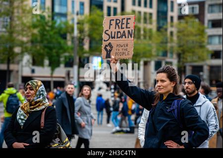 Amsterdam, Niederlande. Oktober 2021. Eine Holländerin sah während der Demonstration ein Plakat zur Unterstützung des Sudan halten.in den Niederlanden lebende Sudanesen versammelten sich auf dem Dam-Platz im Stadtzentrum von Amsterdam, um gegen den Militärputsch im Sudan zu protestieren. Am Montag löste der Putschführer Gen Abdel Fattah Burhan die zivile Herrschaft auf, verhaftete politische Führer und rief den Ausnahmezustand aus. Eine große Zahl von Demonstranten fordert auf den Straßen der Hauptstadt die Rückkehr der zivilen Herrschaft. Kredit: SOPA Images Limited/Alamy Live Nachrichten Stockfoto