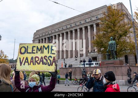 Olemme vaarassa. Klimaprotesten mit Pappschild vor dem Parlamentsgebäude in Helsinki, Finnland. Stockfoto