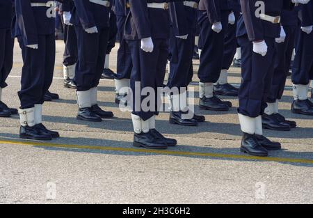 Mitarbeiter der griechischen Marine in blauer Uniform während einer Parade auf einer öffentlichen Straße. Silhouette der Männer der hellenischen Streitkräfte mit schwarzen Stiefeln und weißen Handschuhen. Stockfoto