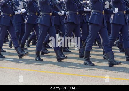 Armee-Kadetten in blauer Uniform während einer Parade auf einer öffentlichen Straße. Silhouette der Männer der hellenischen Streitkräfte mit schwarzen Stiefeln und weißen Handschuhen mit Gewehren. Stockfoto