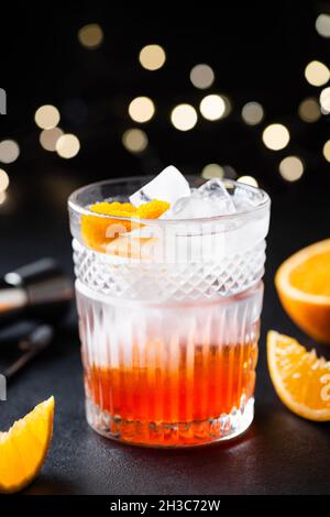 Orange Alkoholcocktail mit Eis in Whiskey-Glas auf schwarzem Hintergrund. Kreatives Fusion-Getränk Stockfoto