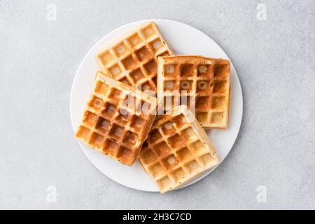 Quadratische belgische Waffeln auf Teller isoliert auf grauem Hintergrund, Draufsicht Stockfoto