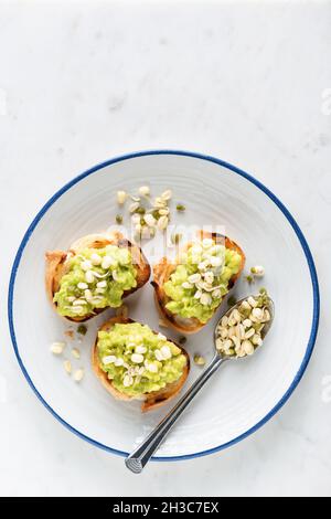 Avocado-Toasts mit Mungbohnensprossen auf einem Teller. Gesunde vegane Vorspeise oder Snack. Draufsicht Kopierraum für Text, grauer Zementhintergrund Stockfoto