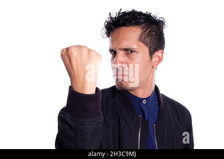 Wütender Mann mit dem Wunsch, mit Faust zu schlagen, isoliert auf weißem Hintergrund. Junger Erwachsener zeigt seine Faust und klammcht sie an die Kamera. Stockfoto