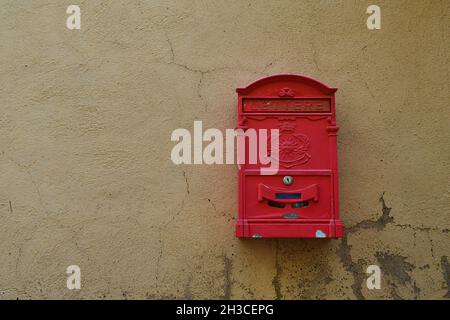 Nahaufnahme eines roten Briefkastens, der an der Wand eines alten Hauses in der Toskana, Italien, hängt Stockfoto