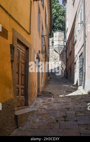 Eine schmale bergauf Gasse im historischen Zentrum des mittelalterlichen Dorfes im Sommer, Castagneto Carducci, Livorno, Toskana, Italien Stockfoto