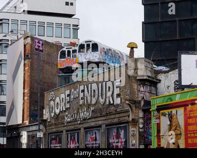 Great Eastern Street in Shoreditch mit den berühmten Lets anbeten und ertragen einander Schild und U-Bahn-Züge über einem Gebäude. London Stockfoto