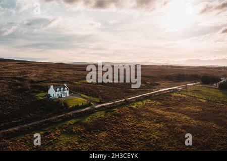 Luftdrohnenaufnahme eines Einzelhauses auf der Isle of Skye, Schottland, Herbst. Sonnenaufgang mit Himmel im Hintergrund Stockfoto