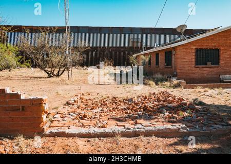 Die US-mexikanische Grenzmauer dient gleichzeitig als Hinterhofzaun eines Hauses in der Kleinstadt Naco, Arizona Stockfoto