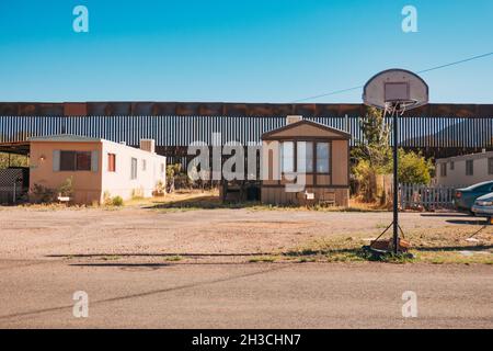 Ein Basketballkorb auf der Straße in der US-Grenzstadt Naco, Arizona. Dahinter ragt die hohe, verrostete Stahlgrenzmauer zwischen den USA und Mexiko Stockfoto