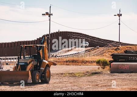 Baumaschinen an der US-mexikanischen Grenzmauer in Naco, Arizona. Ein Grenzschutzfahrzeug überwacht die Wand Stockfoto