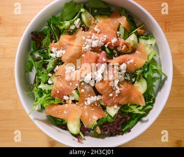 Frischer Salat mit atlantischem geräuchertem Lachs und zerbröseltem Ziegenkäse auf dem Bett aus Frühlingsgesalat Stockfoto