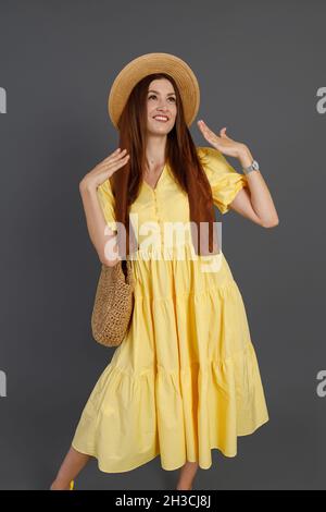 Hübsche Frau in gelbem Kleid steht im Studio Stockfoto