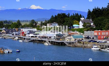 REGENBOGENBRÜCKE BLICK AUF DAS MALERISCHE DORF LA CONNER, WASHINGTON UND DEN SWINOMISH CHANN ... MIT MT BAKER UND DEN WASHINGTON KASKADEN IN DER FERNE. Stockfoto