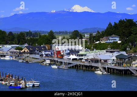REGENBOGENBRÜCKE BLICK AUF DAS MALERISCHE DORF LA CONNER, WASHINGTON UND DEN SWINOMISH CHANN ... MIT MT BAKER UND DEN WASHINGTON KASKADEN IN DER FERNE. Stockfoto
