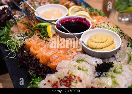 Lachsfilet aus Grawlachs, Weißfischfilet, Hummus, Sektgelee, Sauce aus schwarzer Johannisbeere und Zitrone. Köstliches, professionell aussehendes Essen und Snacks Catering. Stockfoto