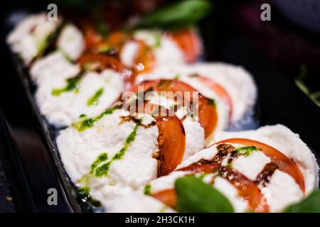 Tomaten-Mozzarella-Salat mit frischem Basilikum und Balsamico-Creme. Köstliche, professionell aussehende Speisen und Snacks werden bei einer Catering-Veranstaltung oder einem Partybuffet serviert Stockfoto