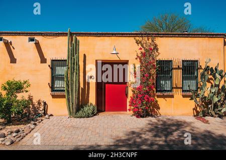 Eine große rote Metalltür bildet einen Kontrast zu den gelben lehmziegelwänden eines Hauses in Barrio Viejo, Tucson, AZ Stockfoto