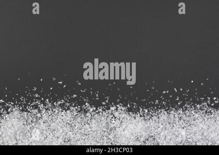 Konfetti oder Kunstschnee auf schwarzem Hintergrund mit Kopierraum. Weihnachtskonzept. Flach liegend, Draufsicht Stockfoto