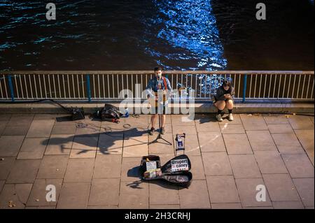 LONDON - 14. SEPTEMBER 2021: Ein Straßenmusiker, der nachts auf der Londoner Southbank singt und Gitarre spielt Stockfoto