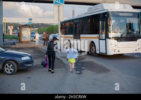 Die Leute sind im Bus. Mutter und Tochter nähern sich dem Busbahnhof. Vorort Stockfoto