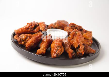 Nahaufnahme von heißen und würzigen Buffalo Chicken Wings auf weißem Hintergrund mit blauem Käse-Dip Stockfoto
