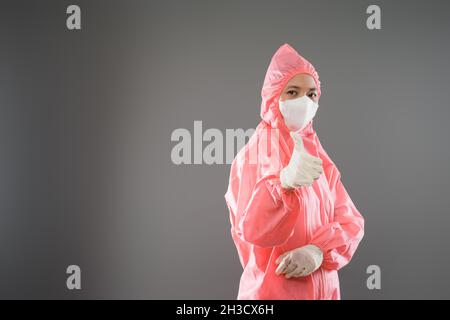 Ein Gesundheitshelfer, der in Schutzausrüstung und Maske mit Daumen nach oben steht Stockfoto