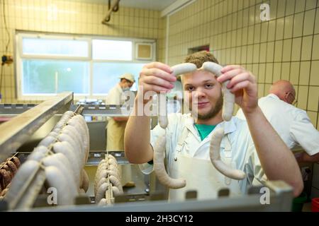 Daaden, Deutschland. Oktober 2021. Auszubildender Nick Mann hängt Würste in der Metzgerei von Dirk Schmidt. Das Unternehmen in Daaden (Kreis Altenkirchen) beschäftigt 30 Mitarbeiter, davon 5 Auszubildende. (An dpa: 'Speeddating and Azubi Car - Creative advertising for New Blood'). Quelle: Thomas Frey/dpa/Alamy Live News Stockfoto