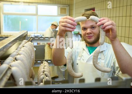 Daaden, Deutschland. Oktober 2021. Auszubildender Nick Mann hängt Würste in der Metzgerei von Dirk Schmidt. Das Unternehmen in Daaden (Kreis Altenkirchen) beschäftigt 30 Mitarbeiter, davon 5 Auszubildende. (An dpa: 'Speeddating and Azubi Car - Creative advertising for New Blood'). Quelle: Thomas Frey/dpa/Alamy Live News Stockfoto