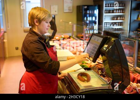 Daaden, Deutschland. Oktober 2021. Auszubildende Sara Katwinkel betreibt die Wurstwaage in der Metzgerei von Dirk Schmidt. Das Unternehmen in Daaden (Kreis Altenkirchen) beschäftigt 30 Mitarbeiter, davon 5 Auszubildende. (An dpa: 'Speeddating and Azubi Car - Creative advertising for New Blood'). Quelle: Thomas Frey/dpa/Alamy Live News Stockfoto