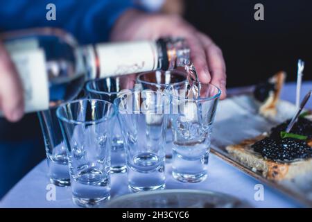 Blick auf die alkoholhaltige Atmosphäre auf dem Catering-Banketttisch, Reihenbestuhlung eines eiskalten Wodkas, dekorierter Catering-Bouquet-Tisch Stockfoto