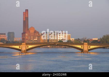 Das ehemalige Kraftwerk Lots Road in Chelsea und die Battersea Bridge über die Themse glühen bald nach Sonnenaufgang in London, England, Gold Stockfoto