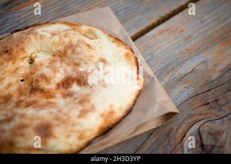 Kaukasisches Fladenbrot auf einem Papierbeutel auf einem Holztisch. Platz für Text kopieren. Stockfoto