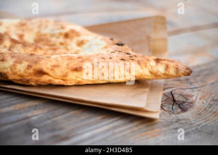 Kaukasisches Pita-Brot auf einem Papierbeutel auf einem Holztisch. Tandoor Fladenbrot. Platz für Text kopieren. Stockfoto