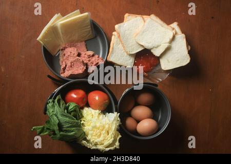 Eine gesunde Ernährung, bestehend aus Hackfleisch, geschnittenem ​​fragrant Weißbrot, Sauce, frischen Hühnereiern, Käse, Senfgemüse, Und Tomaten. Stockfoto