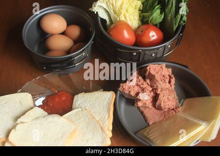 Eine gesunde Ernährung, bestehend aus Hackfleisch, geschnittenem ​​fragrant Weißbrot, Sauce, frischen Hühnereiern, Käse, Senfgemüse, Und Tomaten. Stockfoto