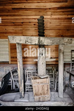 Eine riesige Schraube, die zur Weizenschleifmaschine mit Holzwandhintergrund in einem antiken Dorfhaus gehört Stockfoto