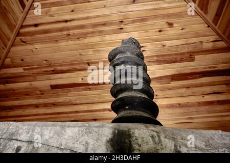 Eine riesige Schraube, die zur Weizenschleifmaschine mit Holzwandhintergrund in einem antiken Dorfhaus gehört Stockfoto