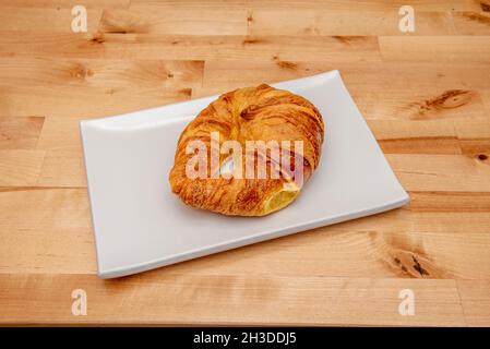 Frisches Buttercroissant auf weißem Teller und Holztisch Stockfoto