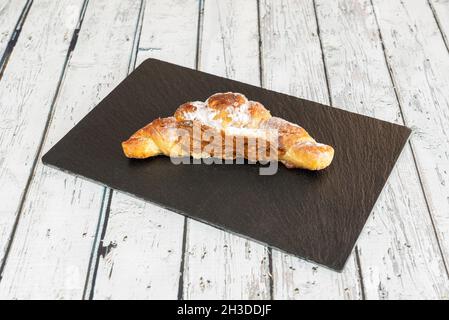 Buttercroissant gefüllt mit Karamellcreme, bestreut mit Zuckerglas Stockfoto