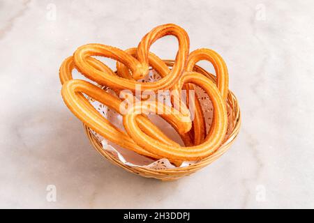 Herzförmiger Churros-Korb zum Frühstück in einem Madrider Restaurant mit weißem Marmortisch Stockfoto