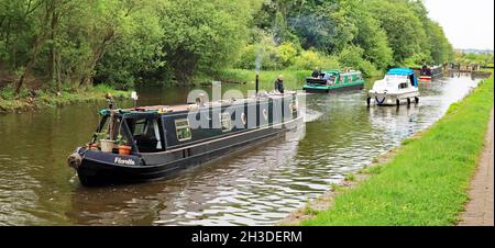 Kanalboote, drei schmale Stahlboote und ein Fiberglas-Kreuzer, die zwischen den Schleusen 81 und 82 auf den Schleusen von Wigan am Leeds und Liverpool vorbeifahren Stockfoto