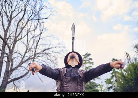 Lustige männliche Performer jonglieren Messer während der Show im Park Stockfoto